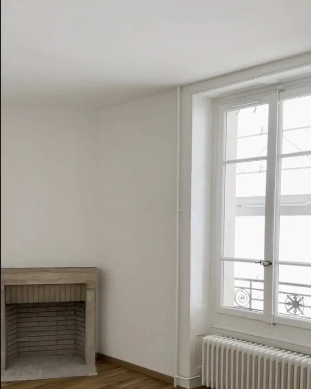 Après : une pièce de l'appartement livrée, murs blancs, fenêtre et radiateur.