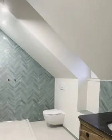 Après : la salle de bains sous les combles refaite, carrelage vert posé en chevrons.