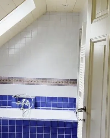 Avant : salle de bains sous les combles, faïence bleue et baignoire.