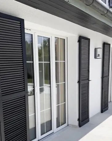 Après : la même façade crépie, volets anthracite et terrasse dallée.