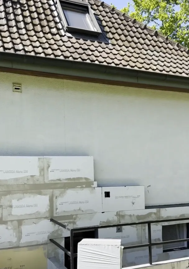 Avant : façade en cours d'isolation, panneaux posés et gaines provisoires.