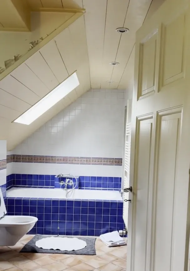 Avant : salle de bains sous combles, faïence bleue et carrelage ancien.