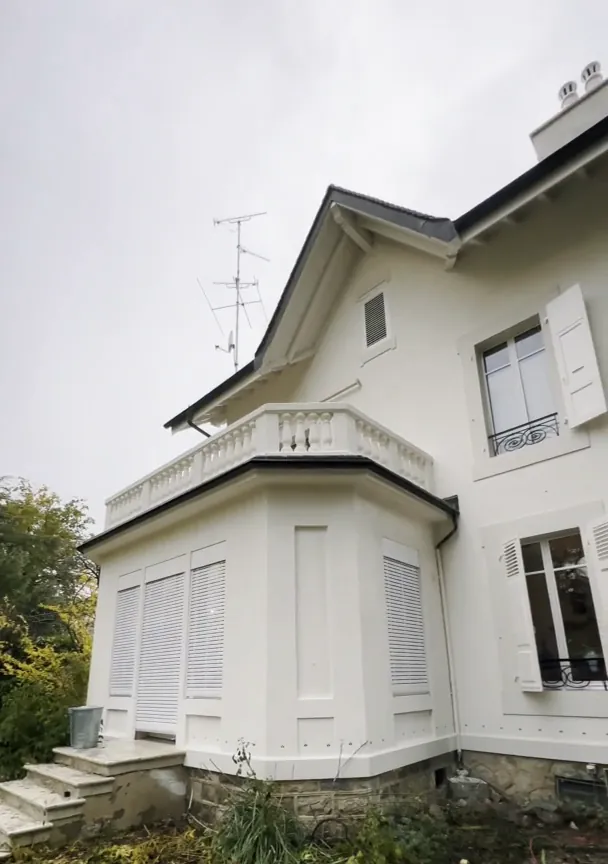 Après : la même villa, façade et volets repeints en blanc.