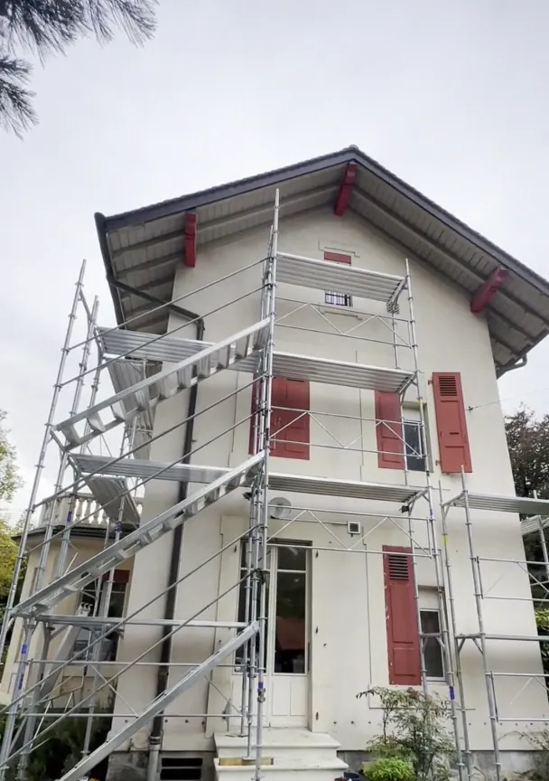 Avant : villa sous échafaudage, volets rouges, façade défraîchie.